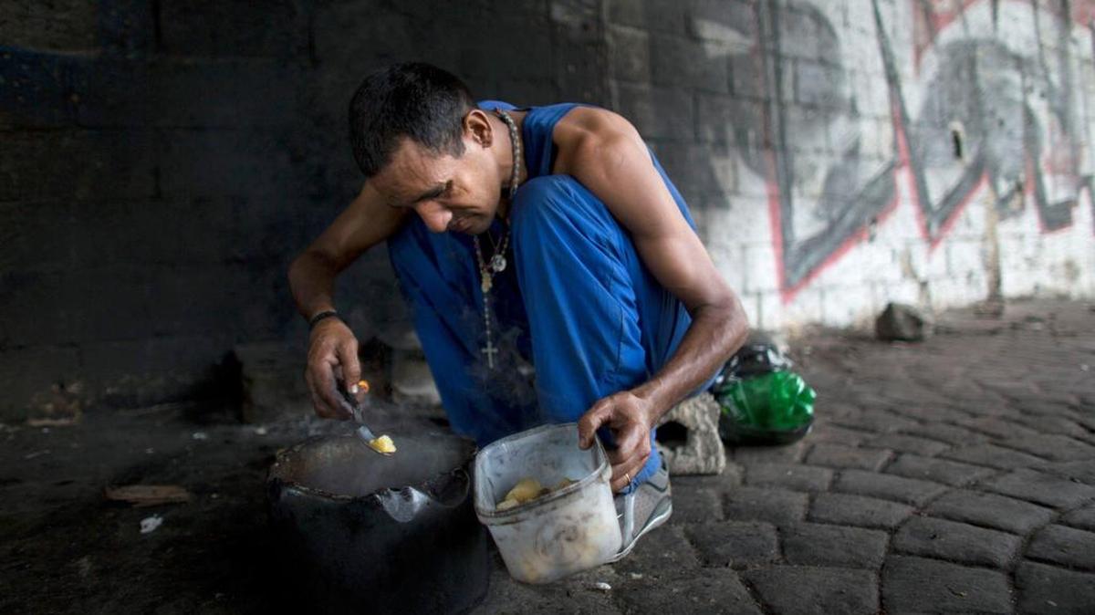 Un hombre identificado como Darwin, de 40 años, se prepara su comida en Caracas, Venezuela,. el 14 de noviembre de 2017. Está desempleado y dijo que perdió su casa hace seis meses y ahora tiene que vivir debajo de un puente.