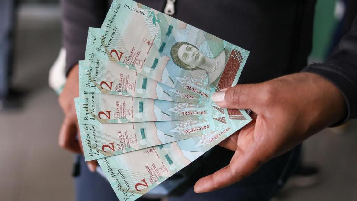 Un cliente de un banco muestra billetes del nuevo cono monetario tras retirar dinero en la entidad el 21 de agosto de 2018, en Caracas (Venezuela).