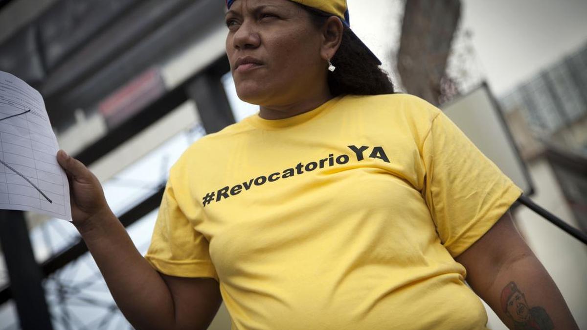 Una mujer con un tatuaje de Hugo Chávez en el brazo recoge firmas para activar el proceso que sacaría de la presidencia a Nicolás Maduro.