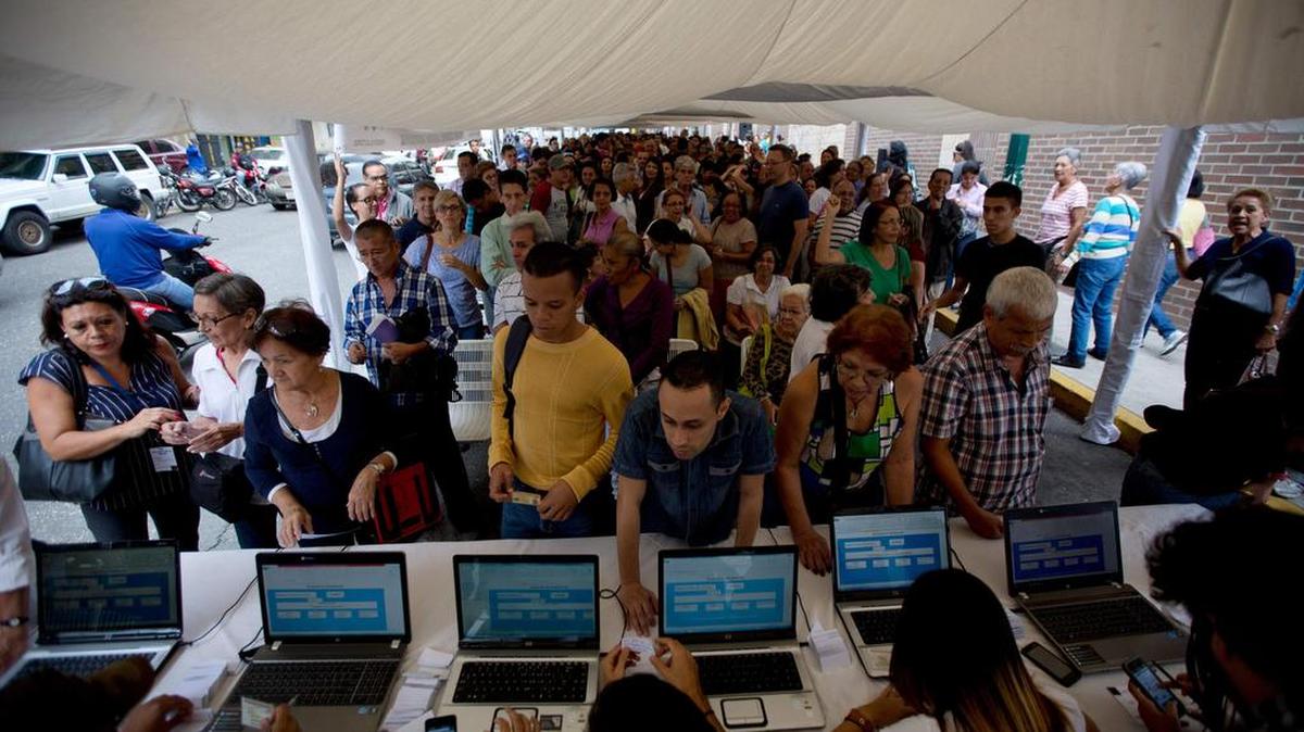 Varias personas se alinean para verificar sus firmas en el centro de datos fuera del Consejo Nacional Electoral de Venezuela, CNE, sede, en Caracas, Venezuela, el lunes 20 de junio de 2016.