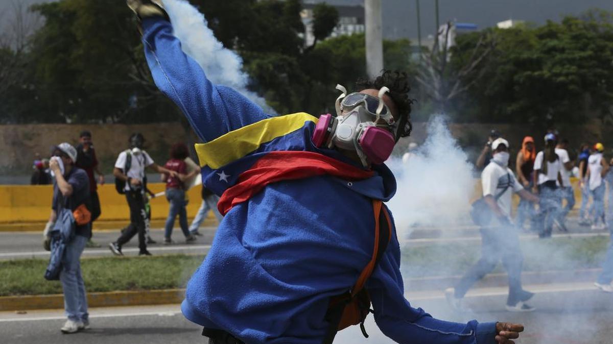 Un manifestante devuelve una bomba de gases lacrimógenos a las fuerzas de seguridad durante las protestas contra el gobierno en Caracas, Venezuela, el miércoles 19 de abril de 2017.