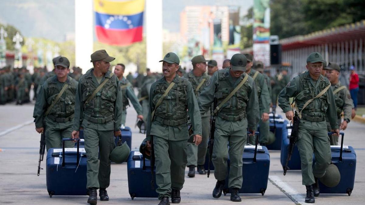 Soldados venezolanos marchan llevando máquinas de votación durante una maniobra preparativa de las elecciones del domingo.
