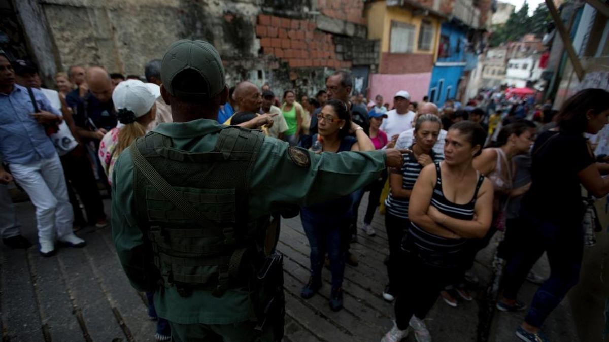 Votantes escuchan instrucciones de un soldado de la Guardia Nacional Bolivariana en espera de votar en las elecciones regionales en Caracas, el 15 de octubre.