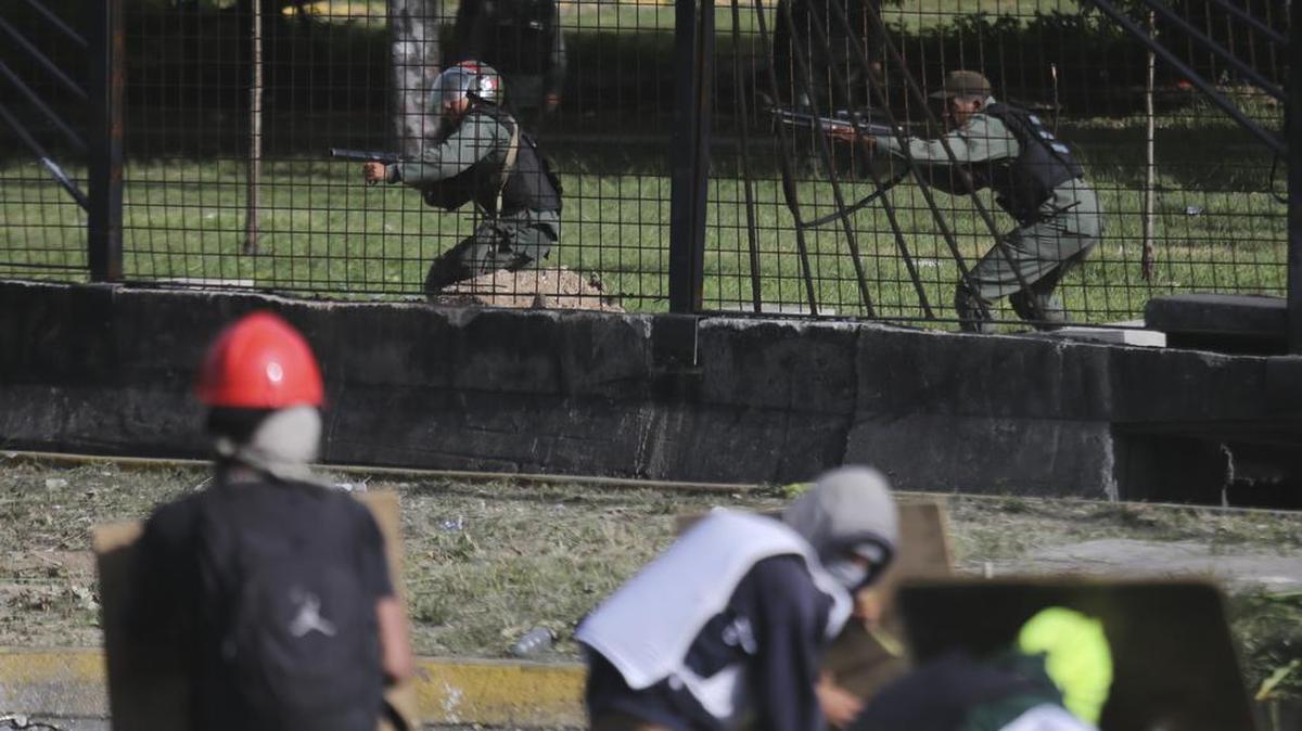 Efectivos de la Guardia Nacional apuntan sus armas contra manifestantes antigubernamentales de la base aérea de La Carlota en Caracas, Venezuela, el lunes 26 de junio de 2017.