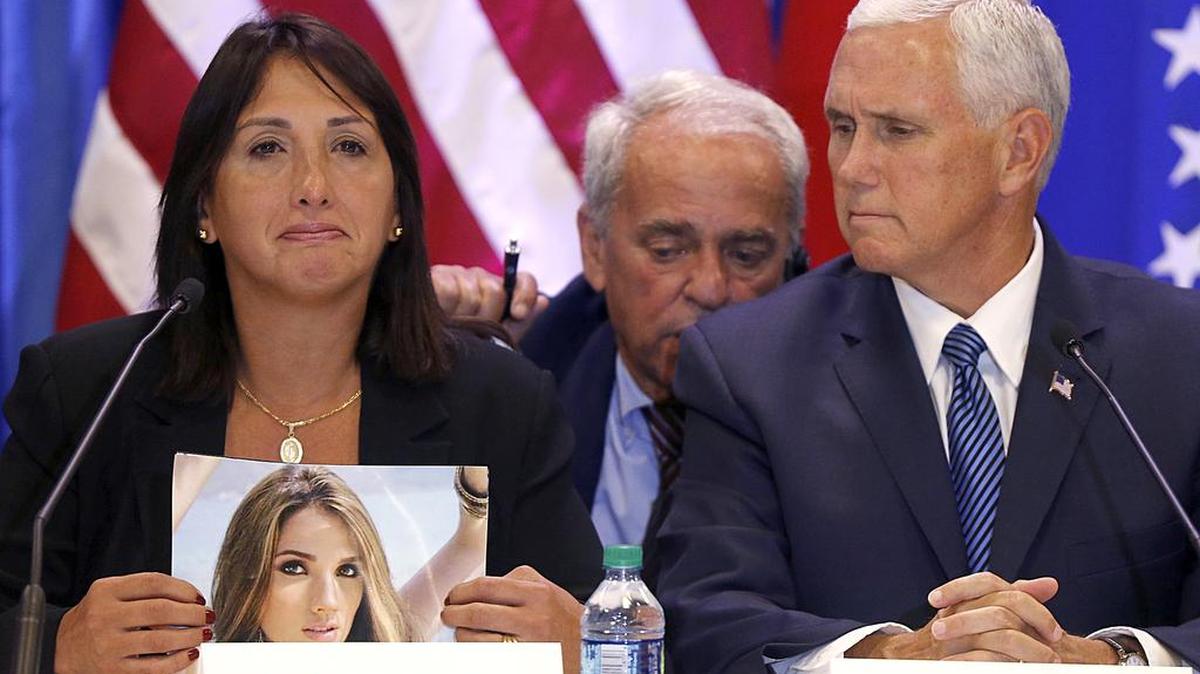 La exiliada venezolana María Eugenia Tovar, a la izquierda, sostiene una foto de su hija, que murió en 2014, junto al vicepresidente Mike Pence, en Doral, Florida, el 23 de agosto de 2017.
