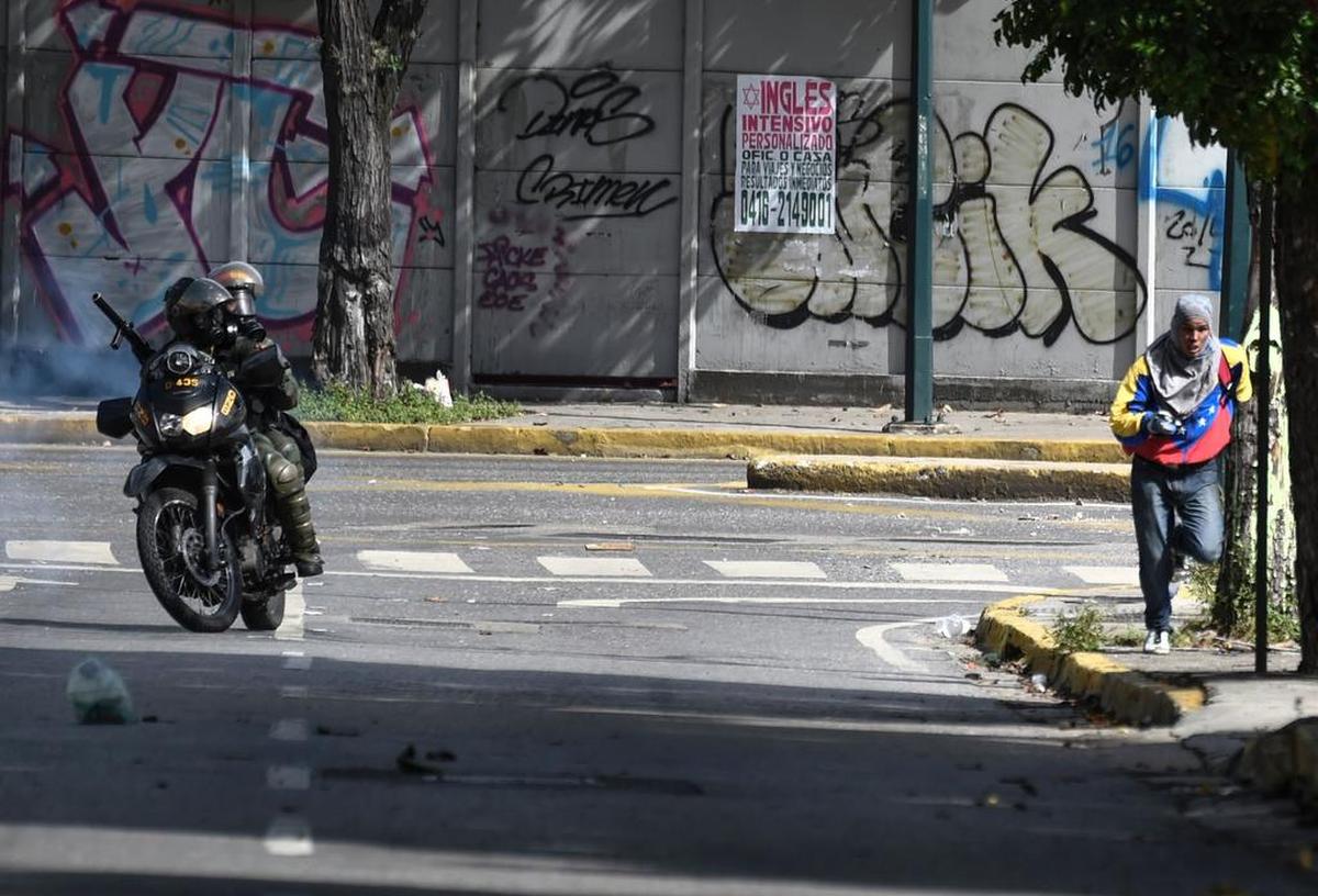 Miembros de la Guardia Nacional Bolivariana persiguen a un manifestante opositor por una calle de Caracas, Venezuela, el lunes 26 de junio de 2017.