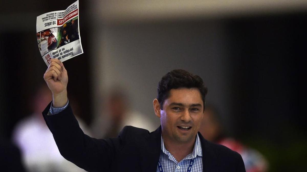 El líder opositor venezolano Carlos Vecchio, exiliado en Miami, muestra un recorte de periódico con una noticia sobre una persona muerta en las protestas en Venezuela durante la 47 Asamblea General de la OEA en Cancún, México, el 21 de junio del 2017.
