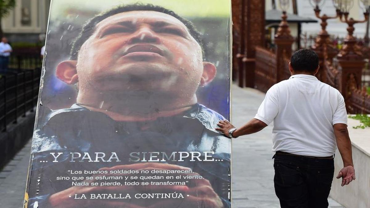 Un empleado de la Asamblea Nacional retira una gran imagen del fallecido presidente Hugo Chávez del edificio legislativo el miércoles.