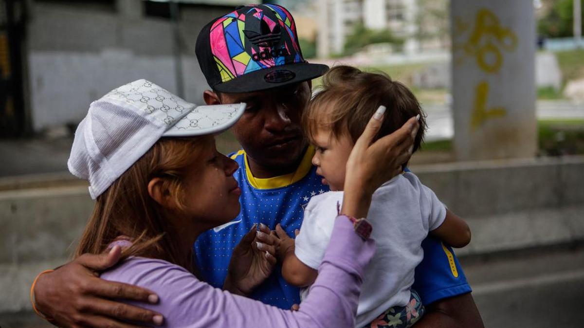 Fotografía del 29 de septiembre de 2017, que muestra a Dayarit Zerpa (i) mientras se despide de su hija de un año y su pareja antes de abordar uno de los autobuses en Caracas (Venezuela) con destino a diferentes países suramericanos.