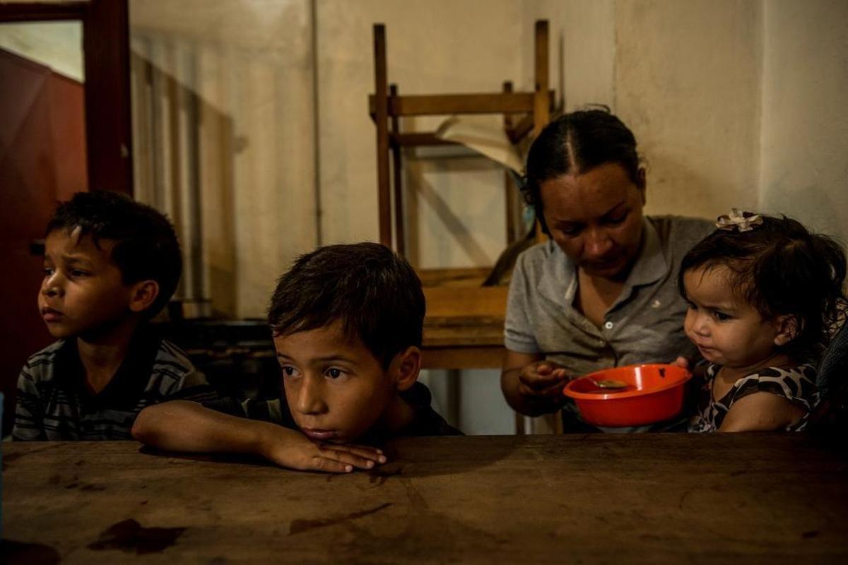 Orianna Caraballo dándole de comer a sus hijos Brayner, Rayman y Sofía en una cocina comunitaria en Los Teques, en septiembre de este año.