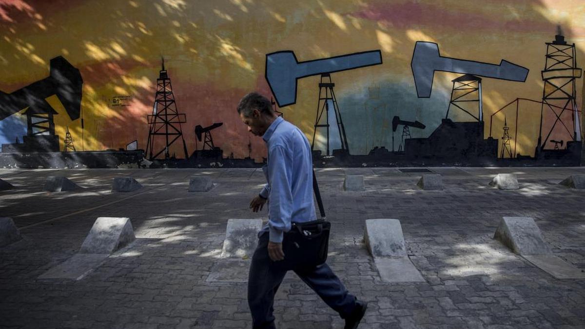 Un hombre camina frente a un mural con diseños del tema de extracción petrolera el 25 de agosto de 2017, en Caracas (Venezuela).
