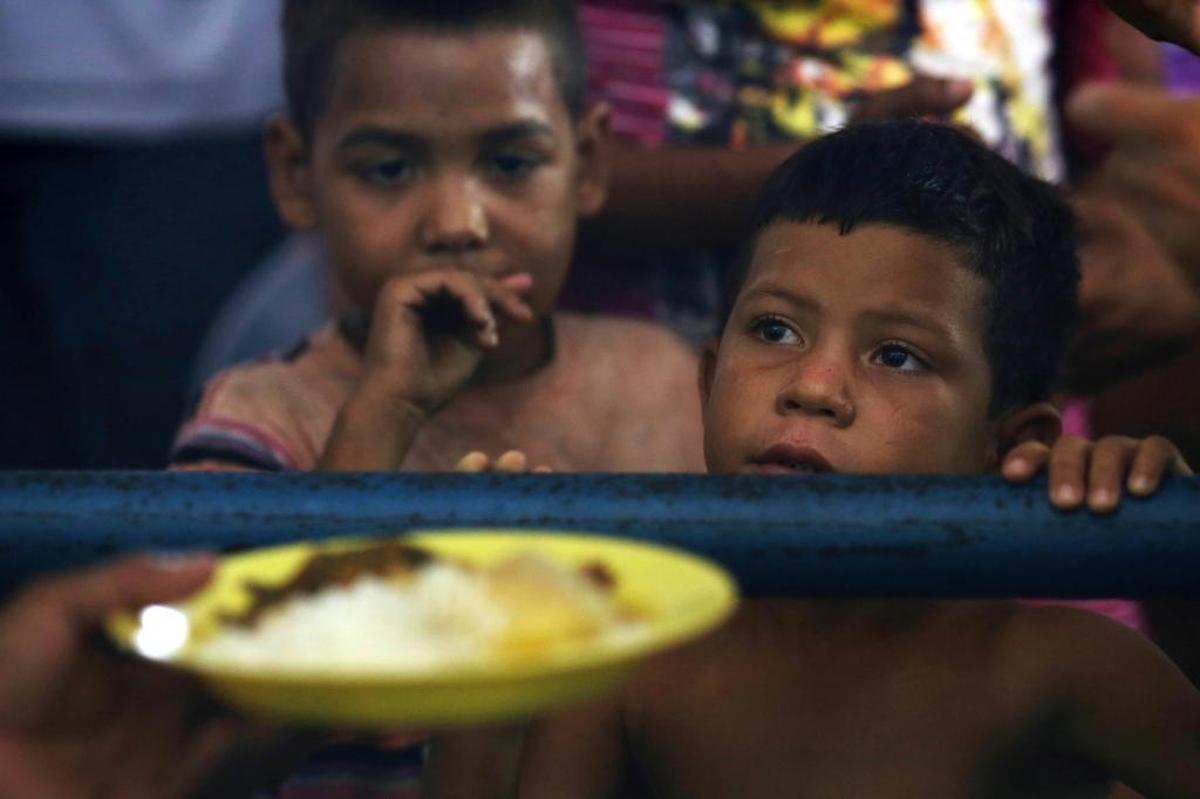 Niños venezolanos esperan recibir comida gratis en en un centro de refugiados en el gimnasio Tancredo Neves, en el estado de Roraima, Brasil, el 8 de marzo del 2018.