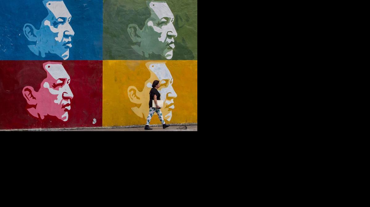 
Fotografía del 3 de marzo de 2015 donde se ve a una mujer caminando frente a un muro con imágenes del fallecido líder venezolano Hugo Chávez en Parque Central en la ciudad de Caracas (Venezuela).
