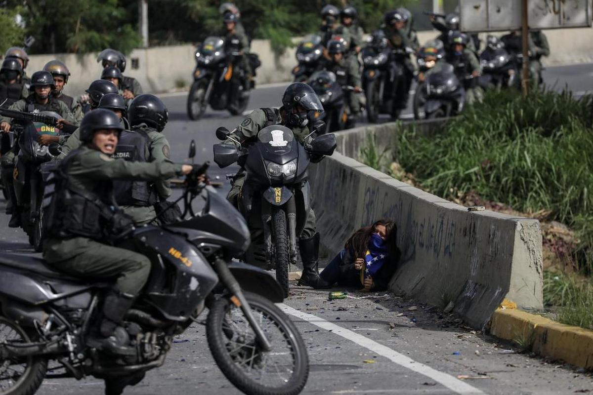 Una joven manifestante es rodeada por una orda de motorizados de la Guardia Nacional Bolivariana el lunes en Caracas, Venezuela.