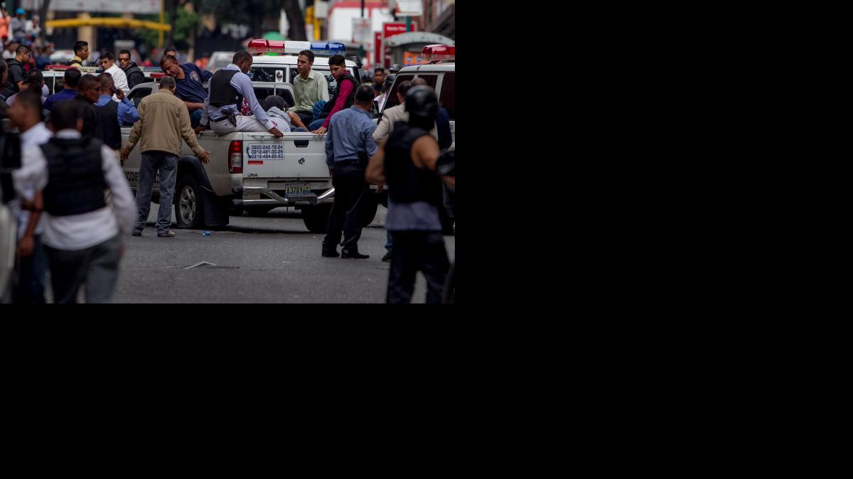 Miembros del Cuerpo de Investigaciones Científicas, Penales y Criminalísticas (CICPC), vigilan en una camioneta a un grupo de capturados, en las inmediaciones del edificio Manfredir donde hubo enfrentamientos con supuestos delincuentes  el, martes 7 de octubre del 2014, en Caracas (Venezuela). 
