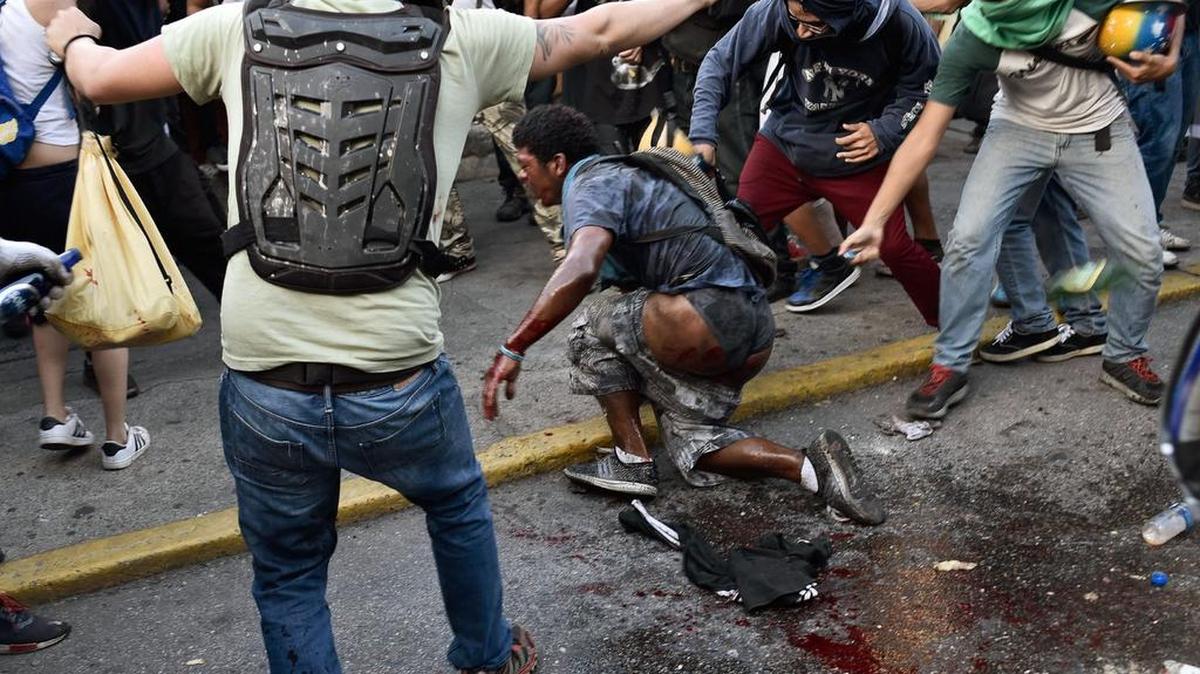 Esta foto de archivo tomada el 20 de mayo de 2017 muestra a manifestantes de la oposición verter gasolina sobre un presunto ladrón durante una protesta contra el gobierno del presidente Nicolás Maduro en Caracas. Según el Ministerio del Interior y Justicia de Venezuela, la víctima, Orlando Figuera, de 21 años, incendiado y acusado de ser un chavista o un ladrón, permanece en el hospital con quemaduras de primer y segundo grado en el 80% de su cuerpo y varias heridas.