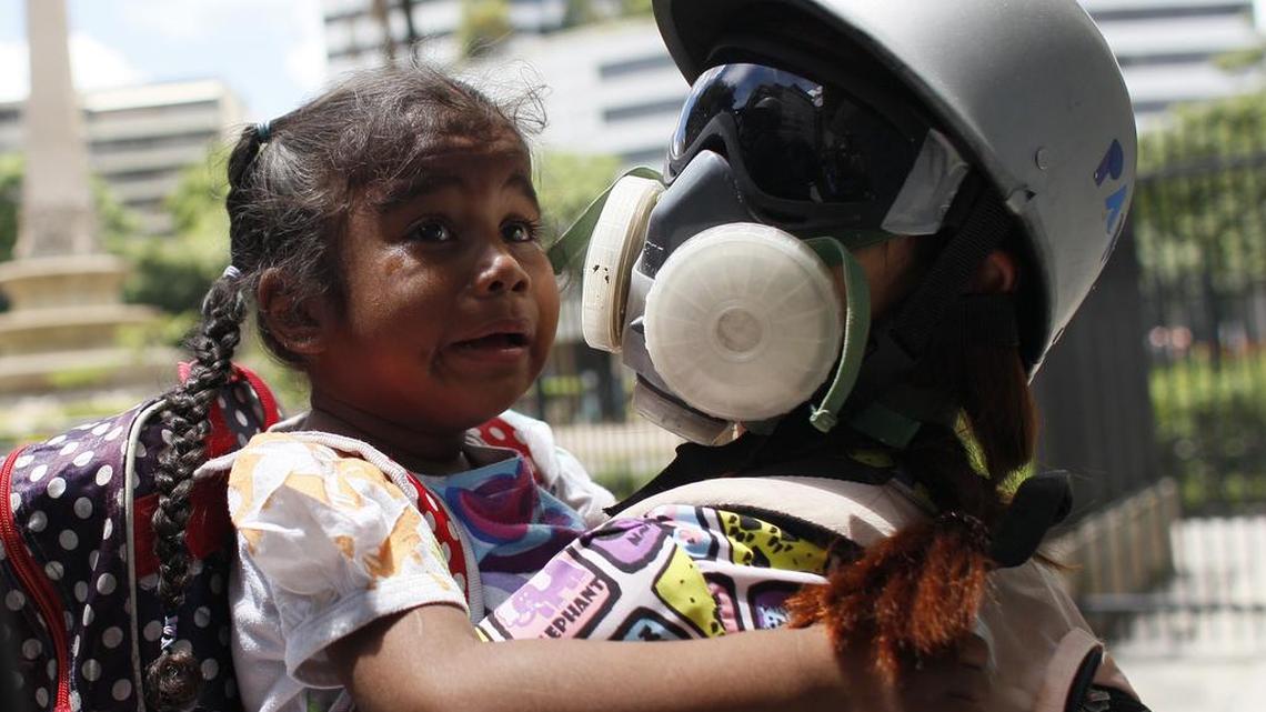 Un paramédico voluntario asiste a una niña afectada por gases lacrimógenos cuando quedó atrapada con su madre en un enfrentamiento entre autoridades y manifestantes antigubernamentales en Caracas, Venezuela, el miércoles 14 de junio de 2017.