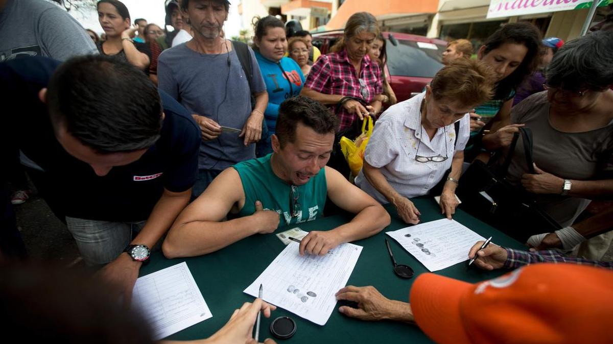 Un grupo de personas firma las planillas para iniciar el referendo revocatorio del gobernante Nicolás Maduro el miércoles 27 de abril en San Cristóbal, Venezuela.