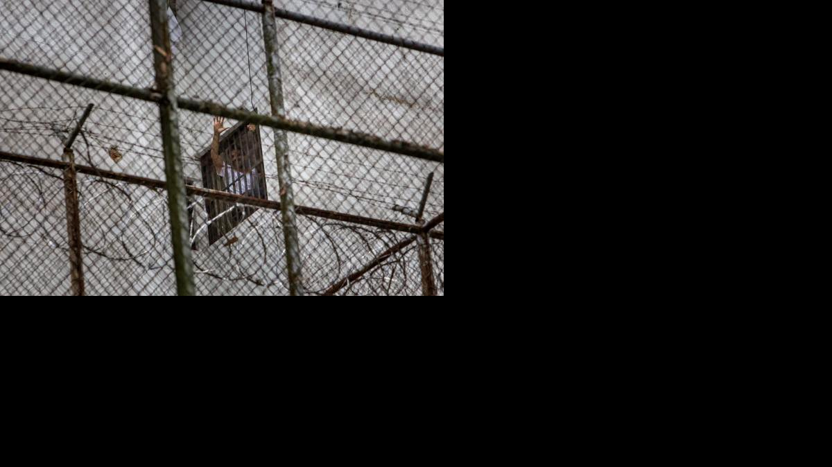 
El dirigente político de oposición Leopoldo Lopez se asoma por una ventana de su celda en la Prisión Militar de Ramo Verde, desde donde saluda a su esposa, Lilian Tintori y su madre, Antonieta Mendoza de López, el sábado 15 de noviembre del 2014, en la ciudad de los Teques (Venezuela).
