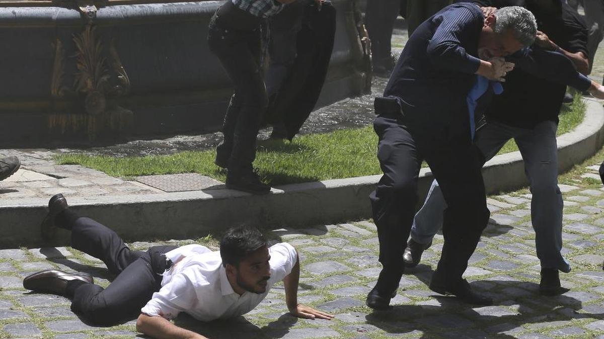 El legislador de la oposición Armando Armas yace en el suelo mientras el legislador Americo De Grazia es agredido por un miembro de la milicia pro-gobierno durante un ataque contra los legisladores de la oposición y los empleados de la Asamblea Nacional en Caracas, Venezuela, el miércoles 5 de julio de 2017.