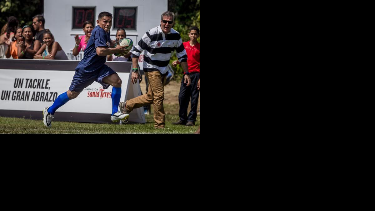 
Marco Reyes, recluso del centro penitenciario Tocorón (c), corre con el balón en sus manos mientras el empresario venezolano Alberto Vollmer (d) le anima, durante un juego de rugby frente al equipo PARC (Proyecto Alcatraz Rugby Club), el 5 de diciembre del 2014, en La Victoria (Venezuela). 
