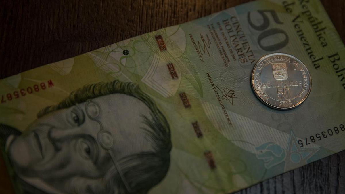 Vista de una moneda de 50 Bolívares junto a un billete de la misma denominación el 28 de diciembre del 2016, en la ciudad de Caracas (Venezuela).