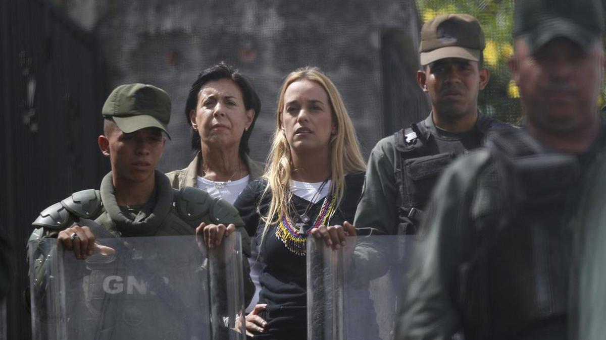 Lilian Tintori, esposa del líder opositor venezolano Leopoldo López, tercera desde la izquierda, y la madre de López, Antonieta Mendoza, segunda desde la izquierda, esperan detrás de oficiales de la Guardia Nacional Bolivariana después de intentar sin éxito visitar al líder opositor en la prisión militar Ramo Verde en Los Teques, en Venezuela, el viernes 28 de abril de 2017.