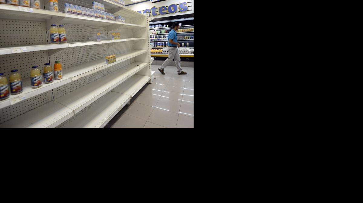 
Un hombre camina al lado de un estante prácticamente vacío en un supermercado en Caracas en enero del 2012.
