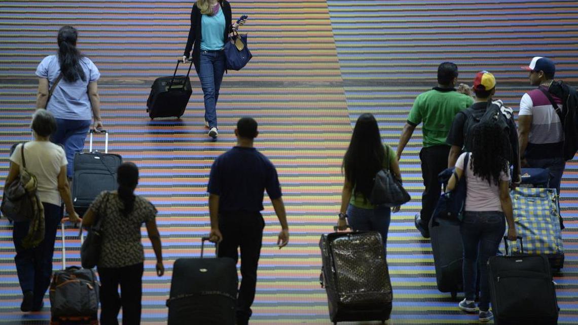 Personas caminando con su equipaje en el Aeropuerto Internacional de Maiquetía, que atiende a Caracas. Una encuesta reciente de Datincorp muestra que un mayor número de venezolanos desea emigrar para escapar de la grave crisis que aflige al país. AFP PHOTO/Leo RAMIREZ (Photo credit should read LEO RAMIREZ/AFP/Getty Images)