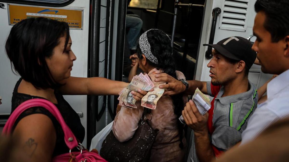 Fotografía del 10 de octubre del 2017, de un grupo de personas que pagan su pasaje para subir a un bus de transporte público en la ciudad de Caracas (Venezuela).