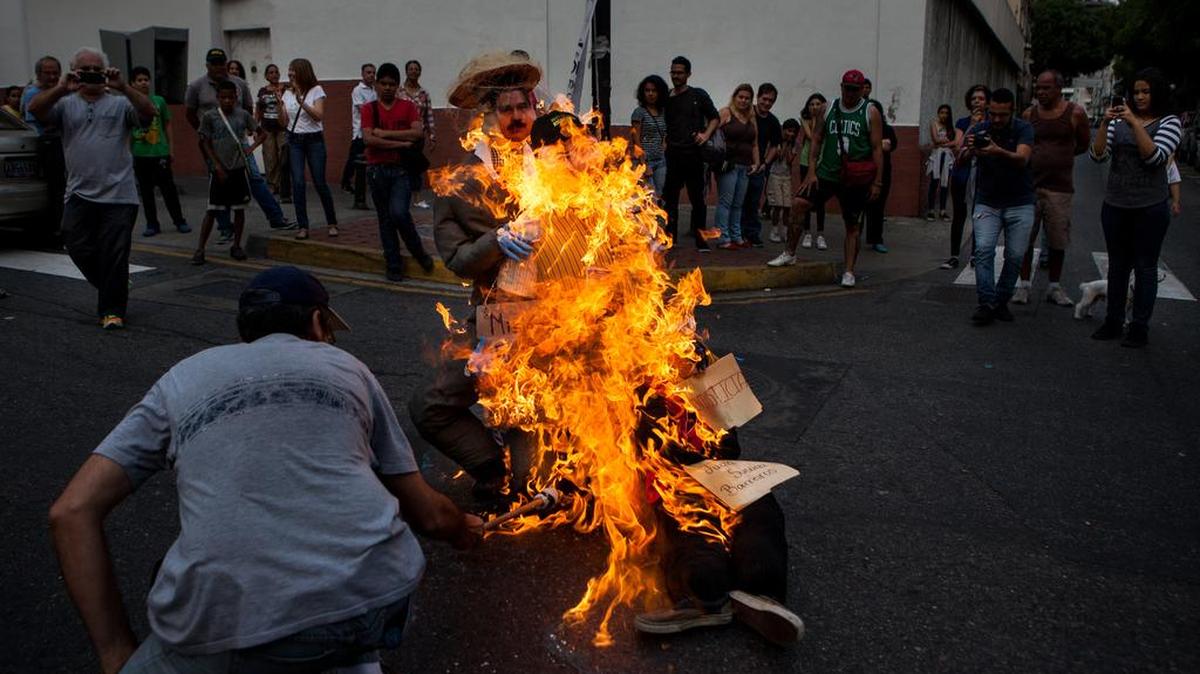 Una figura que representa al presidente de Venezuela, Nicolás Maduro, es quemada por un grupo de personas que participa en la tradicional "Quema de Judas" durante el Domingo Santo hoy, domingo 27 de marzo de 2016, en la ciudad de Caracas (Venezuela).