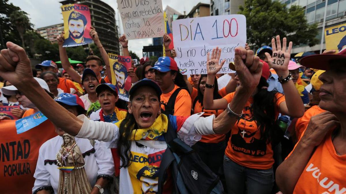Manifestantes de la oposición conmemoran 100 días de protestas callejeras continuas y celebran que el líder de la oposición Leopoldo López fue liberado de la prisión y enviado a casa bajo arresto domiciliario.