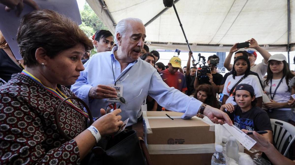 El ex presidente de Colombia Andrés Pastrana, entrega un documento en la mesa de votación durante la consulta popular impulsada por los opositores del presidente Nicolás Maduro el domingo 16 de julio de 2017, en Caracas (Venezuela).