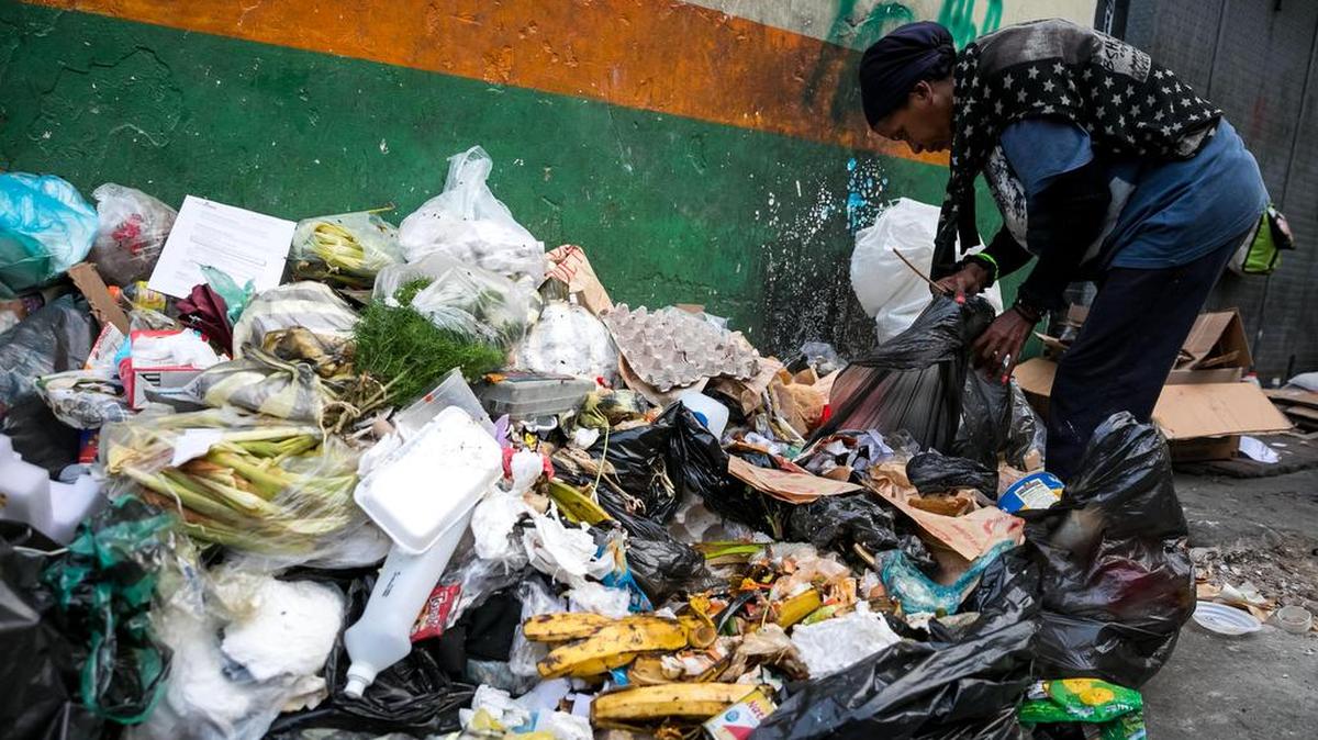 Fotografía fechada el 20 de septiembre de 2017 que muestra a una mujer mientras hurga en una basura en busca de comida en una calle de Caracas (Venezuela).