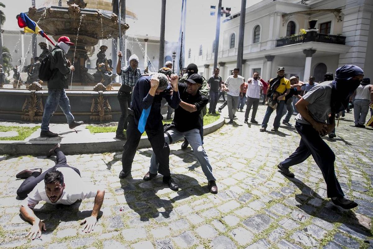 Los diputados Armando Armas (i) y Américo De Grazia (c) son golpeados por manifestantes en el piso en la Asamblea Nacional el miércoles 5 de julio de 2017, en Caracas (Venezuela).