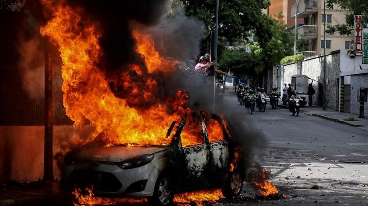 Fotografía de un vehículo en llamas durante un tiroteo el miércoles 14 de junio de 2017, en Caracas (Venezuela). Una concentración de venezolanos opositores al gobierno de Nicolás Maduro se disolvió en la localidad de Altamira, un bastión del antichavismo en el este de Caracas, luego de que se efectuaran varios disparos en el sitio.