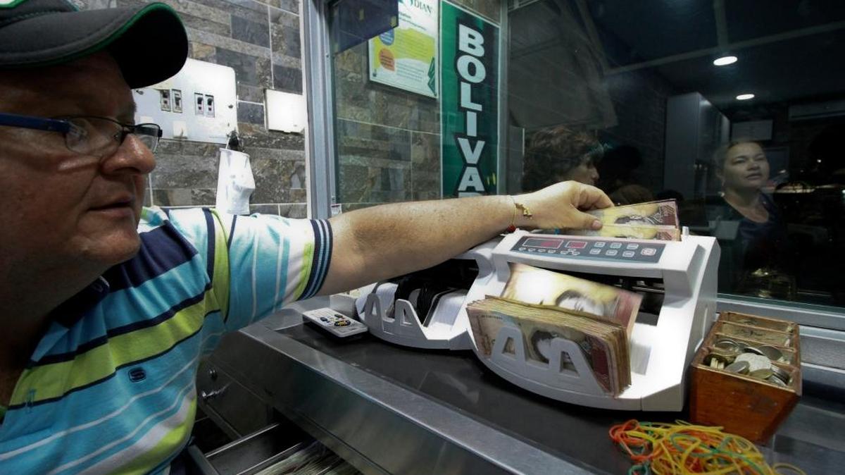 Un hombre cuenta billetes de 100 bolívares en un puesto de cambio en La Parada, en la municipalidad de Villa del Rosario, en Colombia.