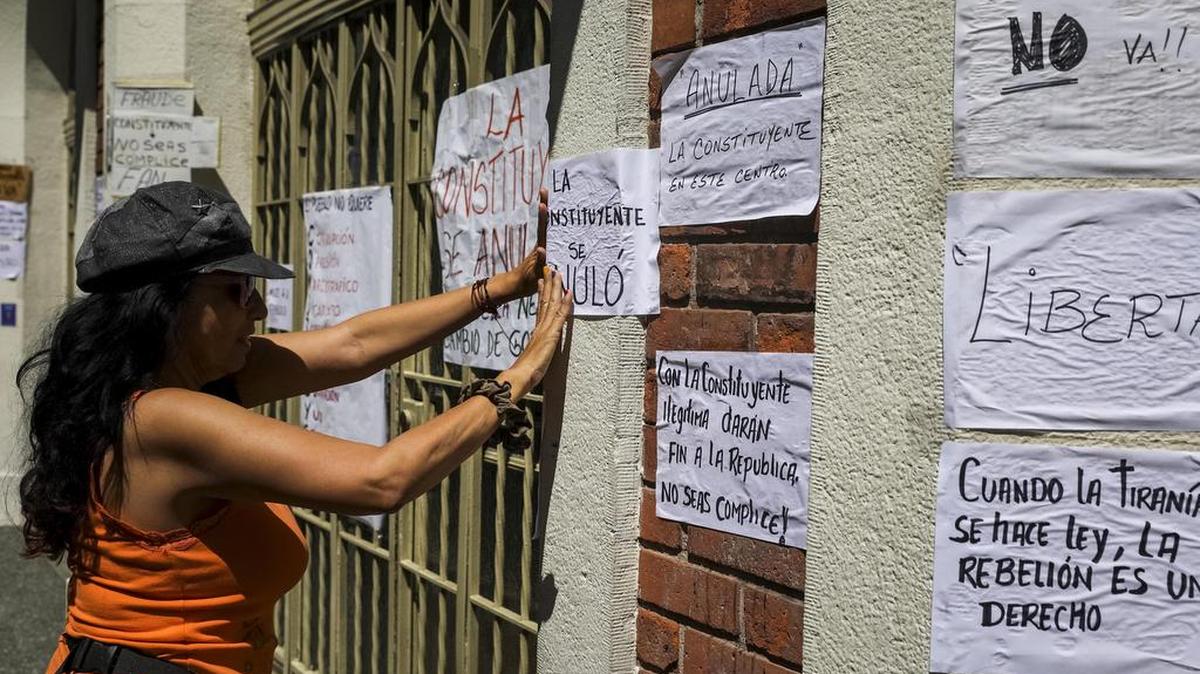Una mujer pega carteles en rechazo a la Asamblea Constituyente el lunes 24 de julio de 2017, en una verja de Caracas (Venezuela).