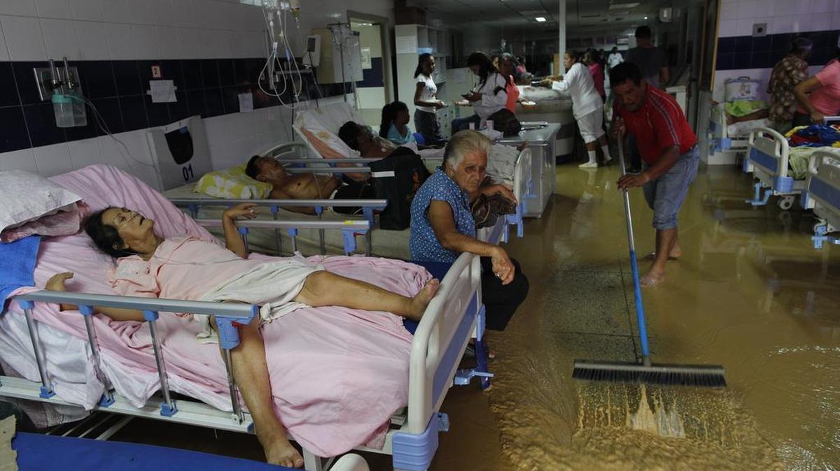 Un familiar de un enfermo en un hospital público saca agua de la sala de emergencias. El hospital de Cumaná, Venezuela, sufre de una grave escasez de medicamentos y falta de higiene.
