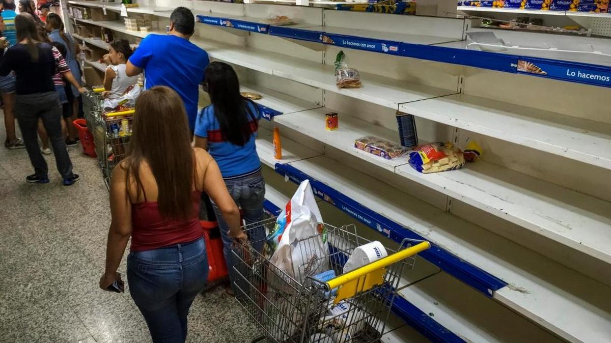 Personas buscan alimentos en un supermercado con estanterías parcialmente vacías el 24 de julio de 2017, en Caracas (Venezuela). Numerosos supermercados de Caracas cerrarán hoy con más estanterías vacías de lo habitual después de que los habitantes de la capital hicieran acopio de alimentos y otros productos básicos ante el paro general contra el Gobierno que la oposición convocó para el miércoles y el jueves.