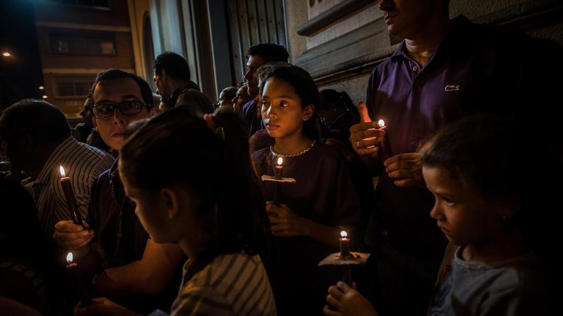 Decenas de personas participan en una procesión de Semana Santa en Caracas, en la noche del miércoles 23 de marzo.