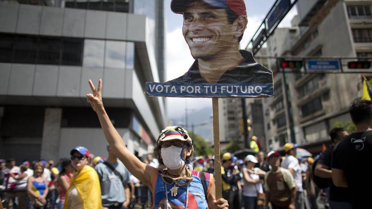 Una mujer sostiene una pancarta con la imagen del líder de la oposición venezolana Henrique Capriles mientras la gente se reúne para una manifestación contra el presidente Nicolás Maduro en Caracas, Venezuela, el sábado 8 de abril de 2017.