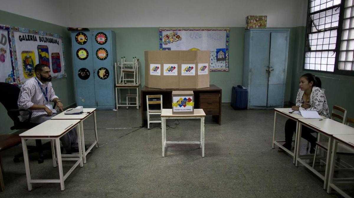 Dos trabajadores electorales esperan por votantes en un centro de votación vacío en Caracas durante las elecciones municipales del 10 de diciembre del 2017.