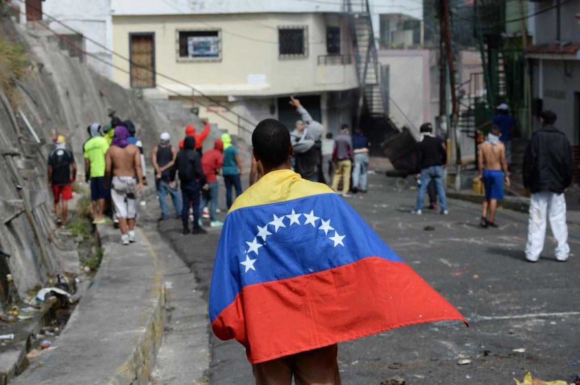 An anti-government demonstrator is wrapped in a Venezuelan flag during clashes with police and troops around a National Guard command post in Cotiza, in northern Caracas, on Jan. 21, 2019. A group of soldiers rose up against Venezuela’s President Nicolas Maduro at a command post in northern Caracas on Monday, but were quickly arrested after posting an appeal for public support in a video, the government said.