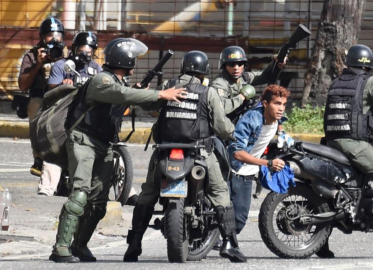 Un opositor trata de huir de la custodia de la Guardia Nacional el lunes en Caracas.