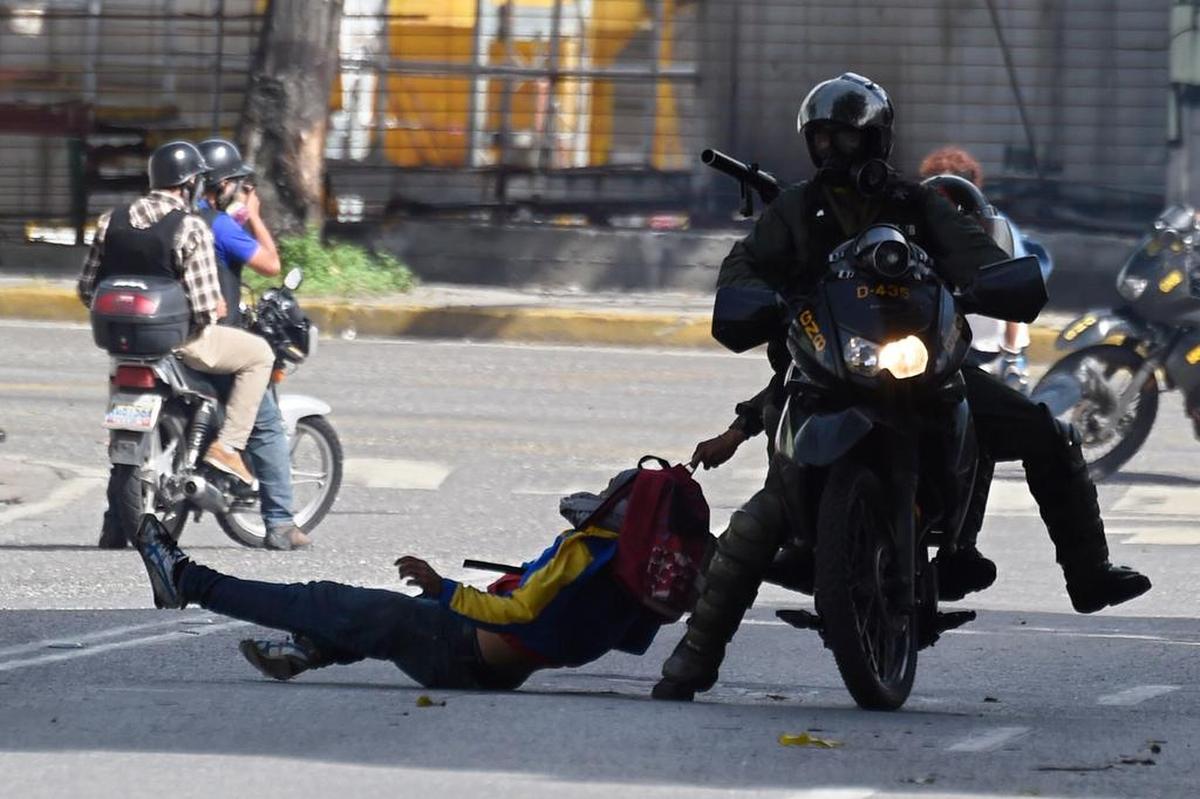 Miembros de la Guardia Nacional Bolivariana arrastran violentamente a un manifestante opositor por una calle de Caracas, Venezuela, el lunes 26 de junio de 2017.