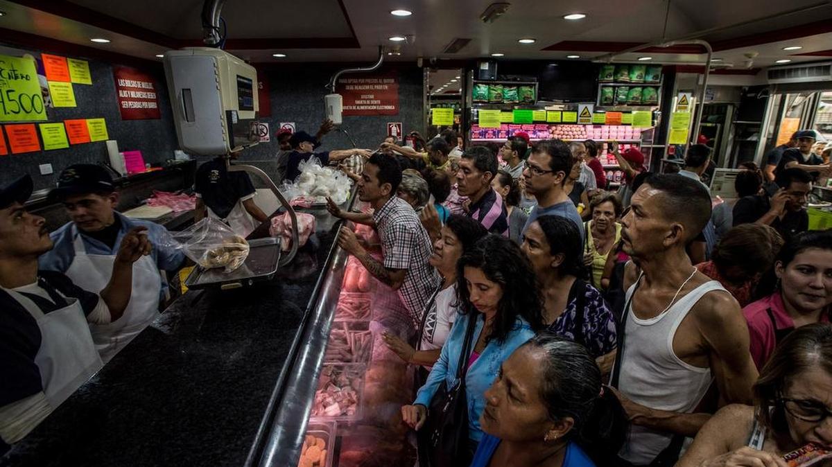 Un comercio atestado por clientes que esperan comprar pollo a precio controlado en Caracas.
