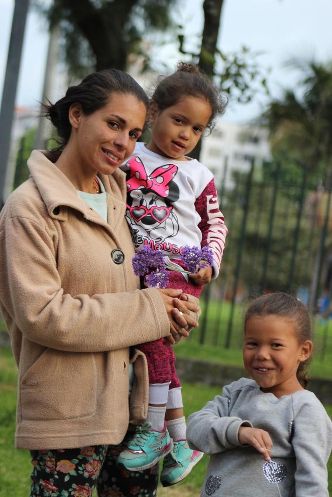 Esperanza Tello sostiene a su bebé Ediangelis Alexandra Rojas y posa junto a su hija Edilianys Rojas en las afueras de una terminal de buses en Bogotá.