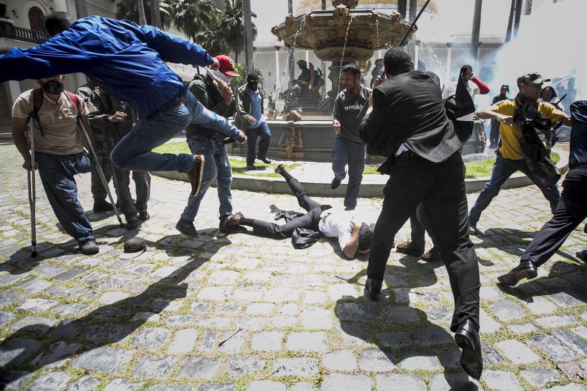El diputado Armando Armas (camisa blanca) es golpeado por manifestantes en el piso en la Asamblea Nacional el miércoles 5 de julio de 2017, en Caracas (Venezuela).