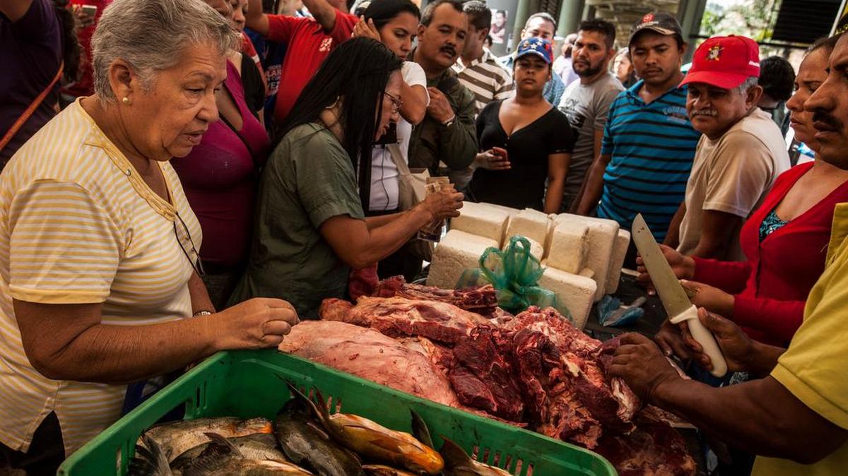 Personas hacen fila para comprar pescado, carne y otros productos en un mercado en Caracas.